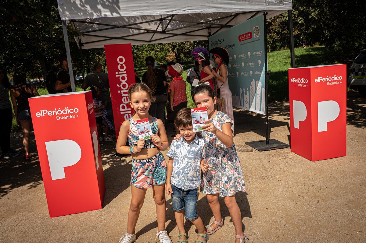 Tres niños posan con la portada de EL PERIÓDICO en la Fiesta Mayor de Bellvitge.