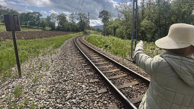 Una mujer señala el trazado de la antigua vía de Feve a su paso por Nava. | J. A. O.