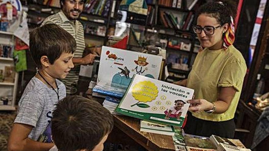 Un padre acude con sus hijos a comprar el material escolar del próximo curso en una librería.