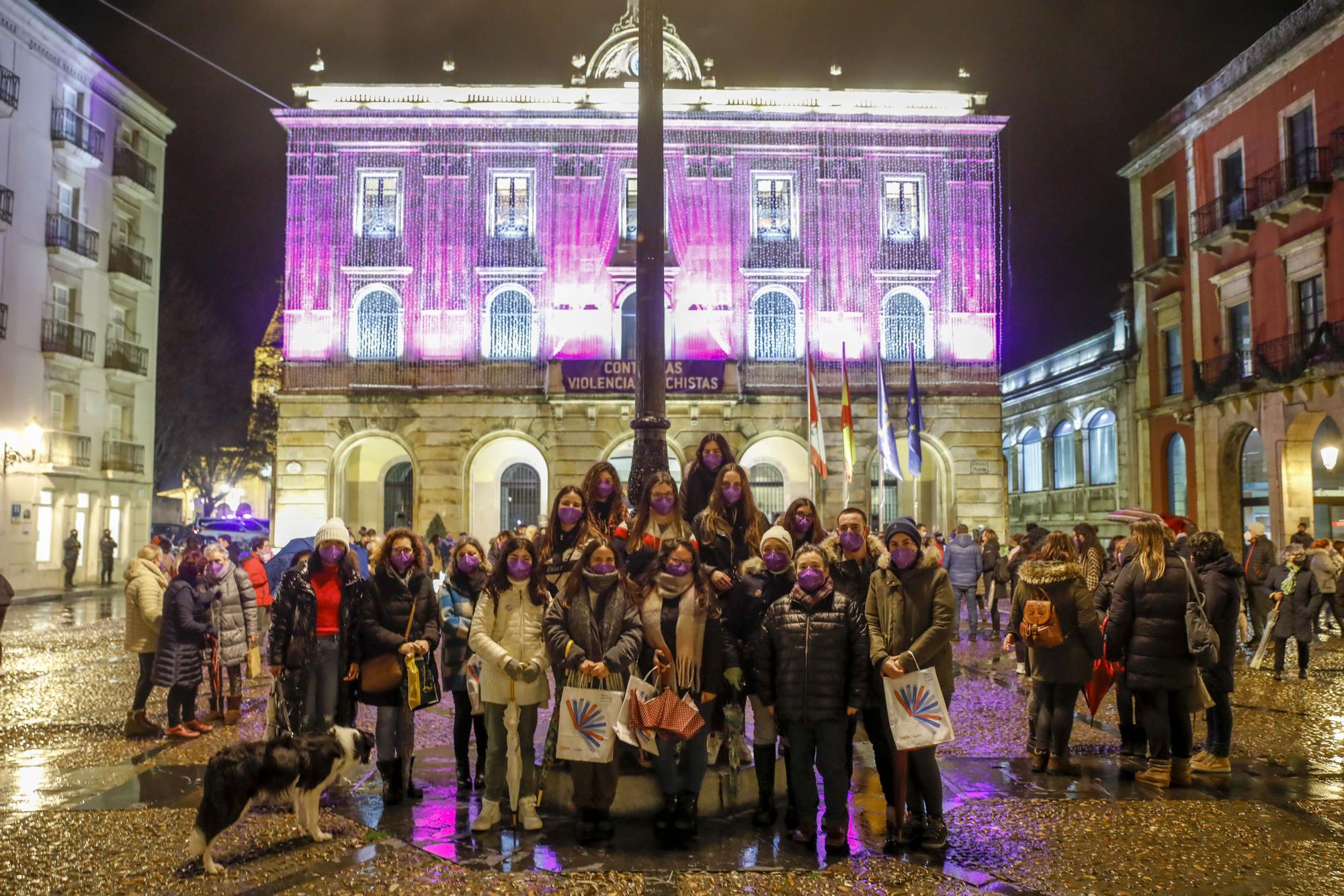 Un grupo de mujeres, delante del Ayuntamiento tintado de morado