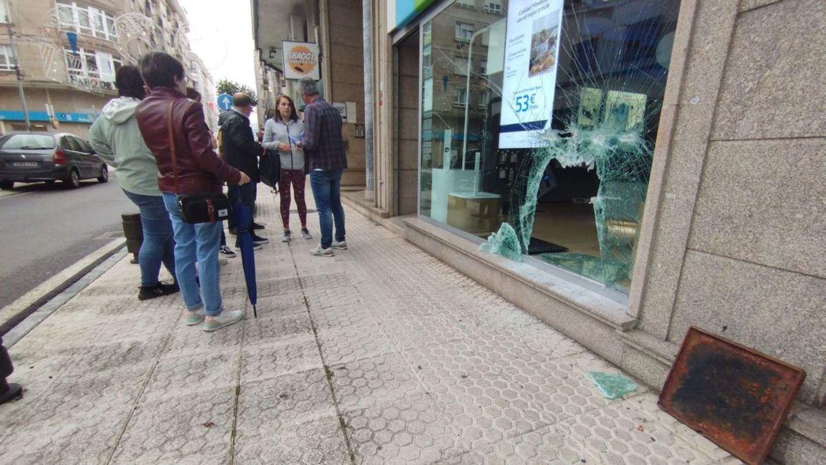 La policía toma declaración a los vecinos ante la tienda y la tapa de alcantarilla.