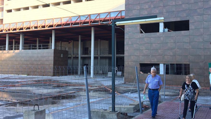 Varios pacientes pasan junto a las obras del hospital, paralizadas desde hace unos diez años.