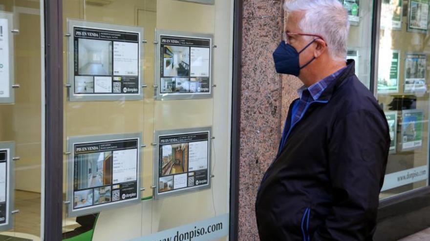 Una persona mirant les ofertes de pisos a l’aparador d’una immobiliària. | MARTA CASADO PLA/ACN