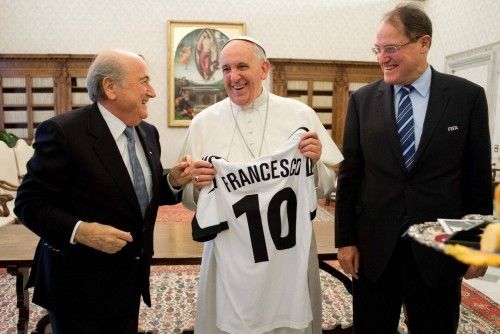 Pope Francis smiles as he receives a soccer jersey by FIFA President Sepp Blatter during a private audience at the Vatican