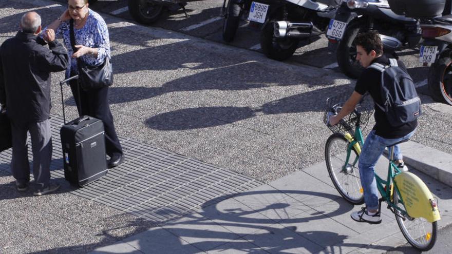 Un ciclista circulant per la vorera a Girona.