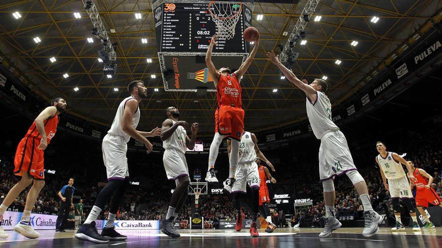 El escolta francés del Valencia Basket, Antoine Diot (centro), lucha por un rebote ante el alero polaco del Unicaja, Adam Waczynski (dcha).