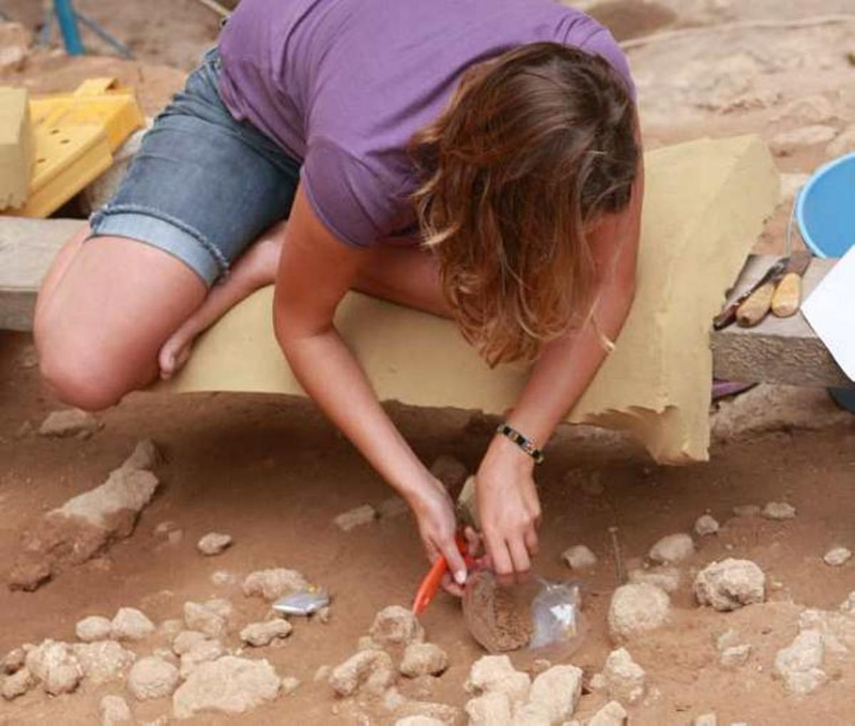 Una arqueóloga recogiendo materiales en un nivel del yacimiento