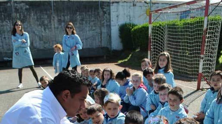 Mauricio González pone la peonza en la mano de un escolar en el colegio José García Fernández de Luarca.