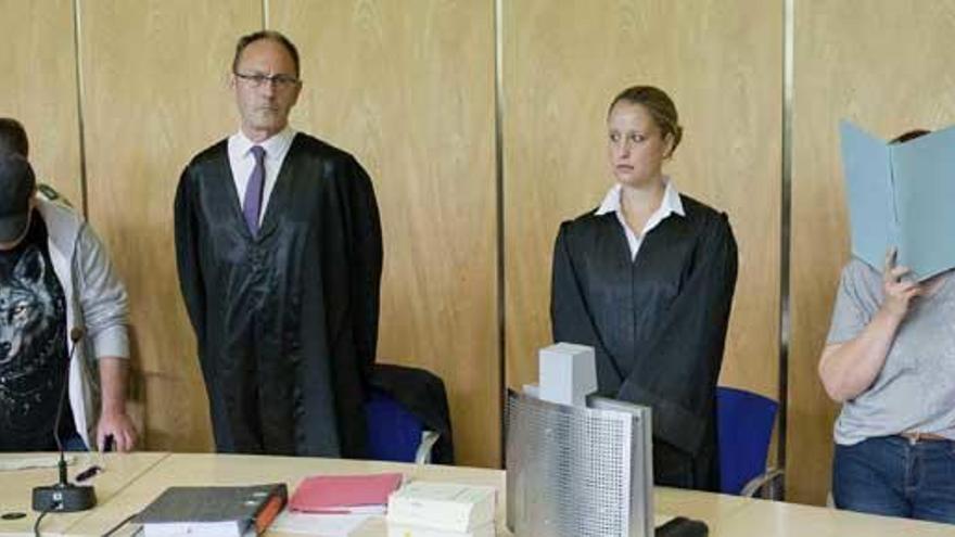 La pareja, con los rostros cubiertos, junto a sus abogados.