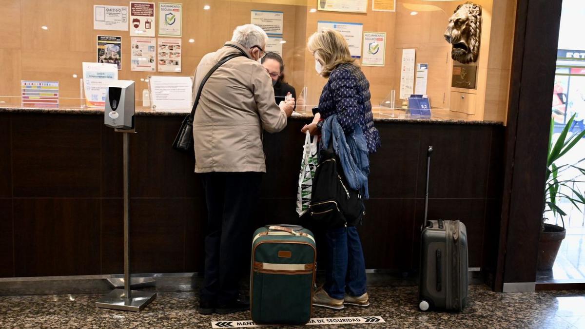 Dos turistas en el pasado otoño, en la entrada de un hotel de Santiago de Compostela. |   // RAFA VÁZQUEZ