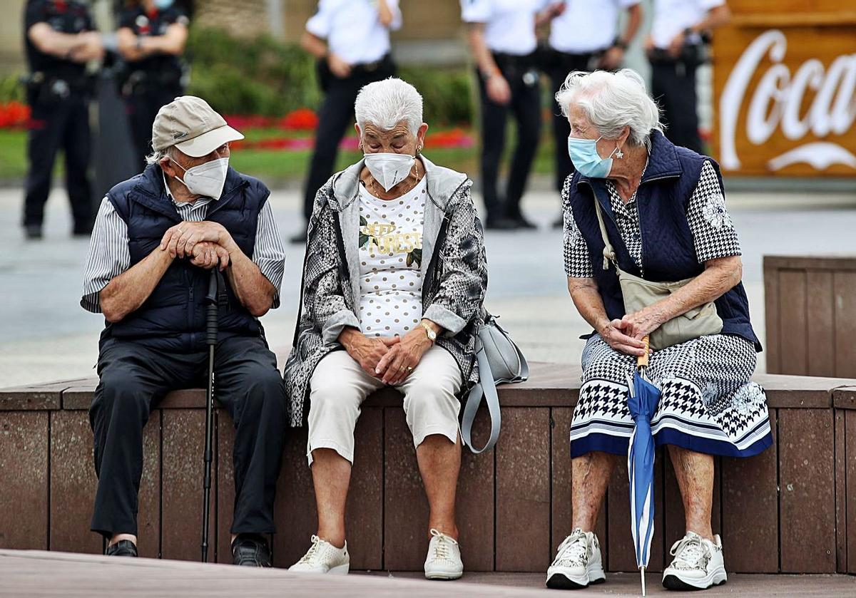 Un grupo de personas mayores, de charla y protegidos con mascarillas.