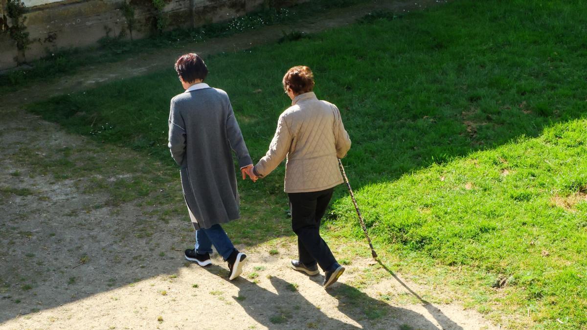 Una mujer acompaña de la mano a otra de avanzada edad en Santiago. Foto de recurso. Tercera edad. Dependencia