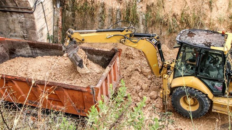 Una máquina excavadora retirando las tierras caídas a la entrada de los túneles de Batoy