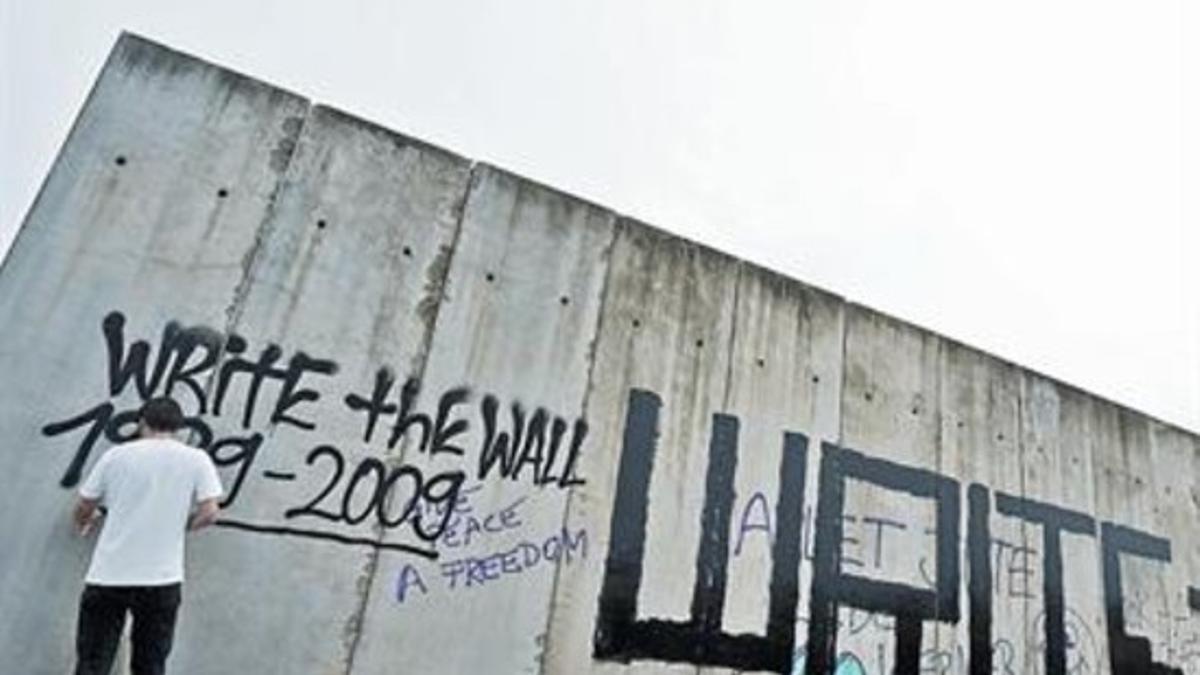 visitante pinta en restos del muro que dividió la ciudad de Berlín.