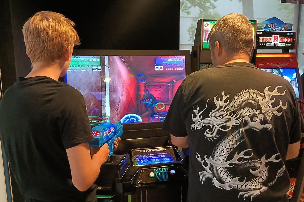 Dos visitantes disfrutan de una máquina arcade de disparos en el salón de Factoría Retro, en Alcorcón (Madrid)