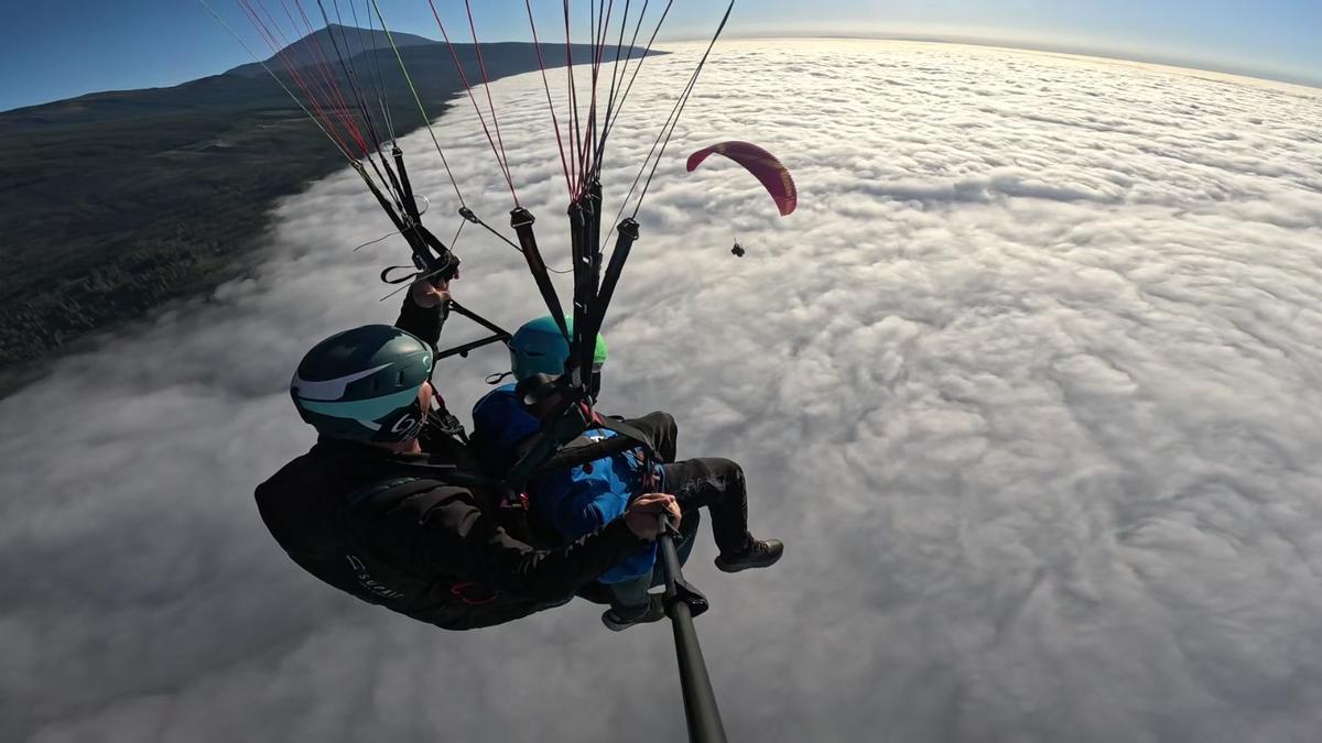 Instructor y aprendiz en pleno vuelo con el mar de nubes debajo y el Teide al fondo