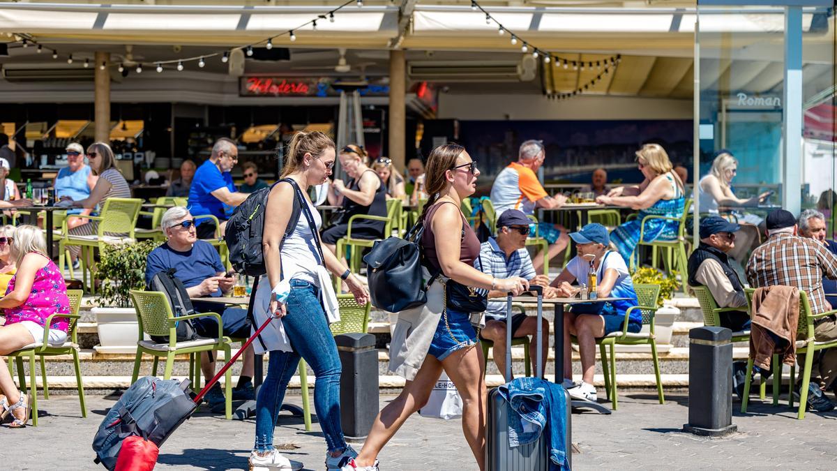 Una pareja de turistas camina con sus maletas por Benidorm