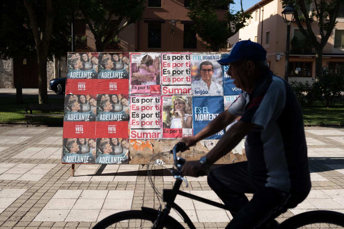 Un ciclista pasa por delante de la propaganda electoral de las elecciones generales del 23J.