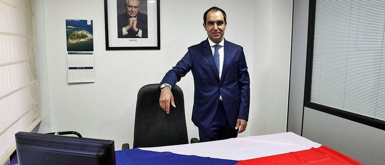 Luis Castaño, en el consulado de la República Checa en Gijón, con una bandera del país centroeuropeo sobre su mesa.