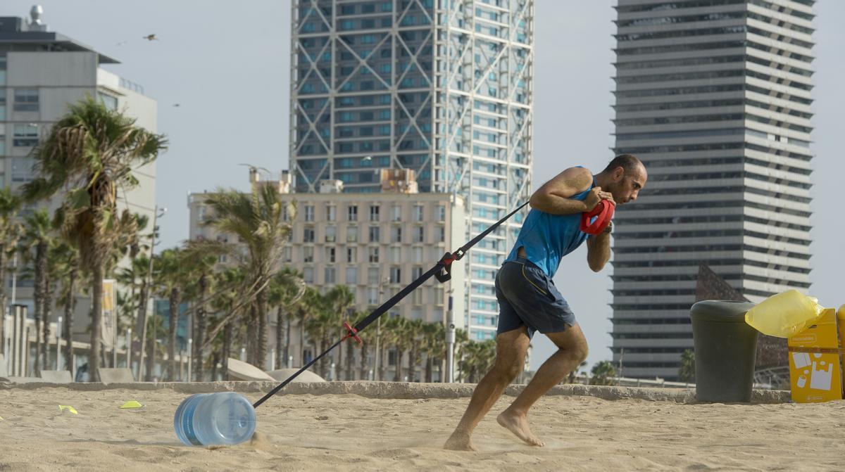 Uno de los ejercicios con bidones de 8 litros en la playa de la Barceloneta