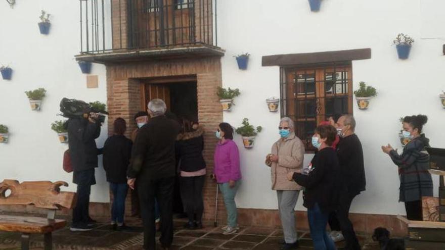 Vecinos cantando villancicos acompañan al reparto de los jamones, ante la expectación de los medios de comunicación.