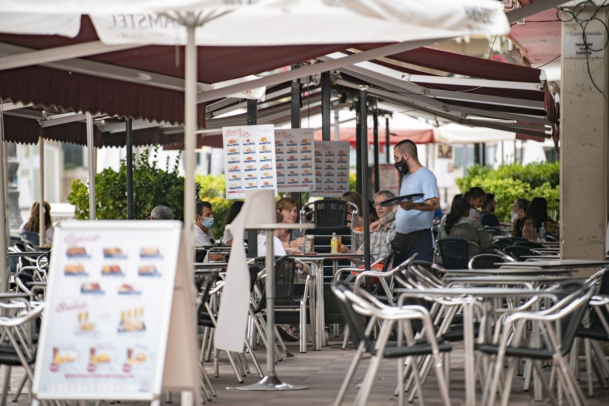 Un camarero en una terraza de una cafetería