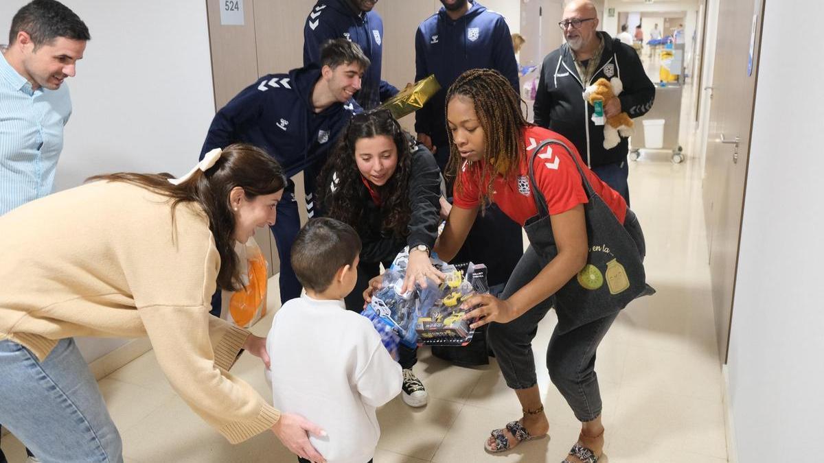 Los jugadores del EÓN Horneo Alicante entregan juguetes a un niño en el IMED Levante de Benidorm