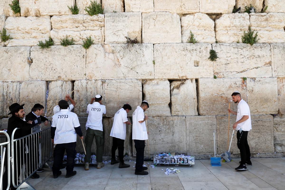 Trabajadores retiran notas de las grietas del Muro de los Lamentos para dejar espacio, como parte de los preparativos previos a la festividad judía de la Pascua, en la Ciudad Vieja de Jerusalén.