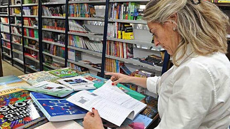 Una mujer ojea un libro de texto escolar en una librería de Murcia.