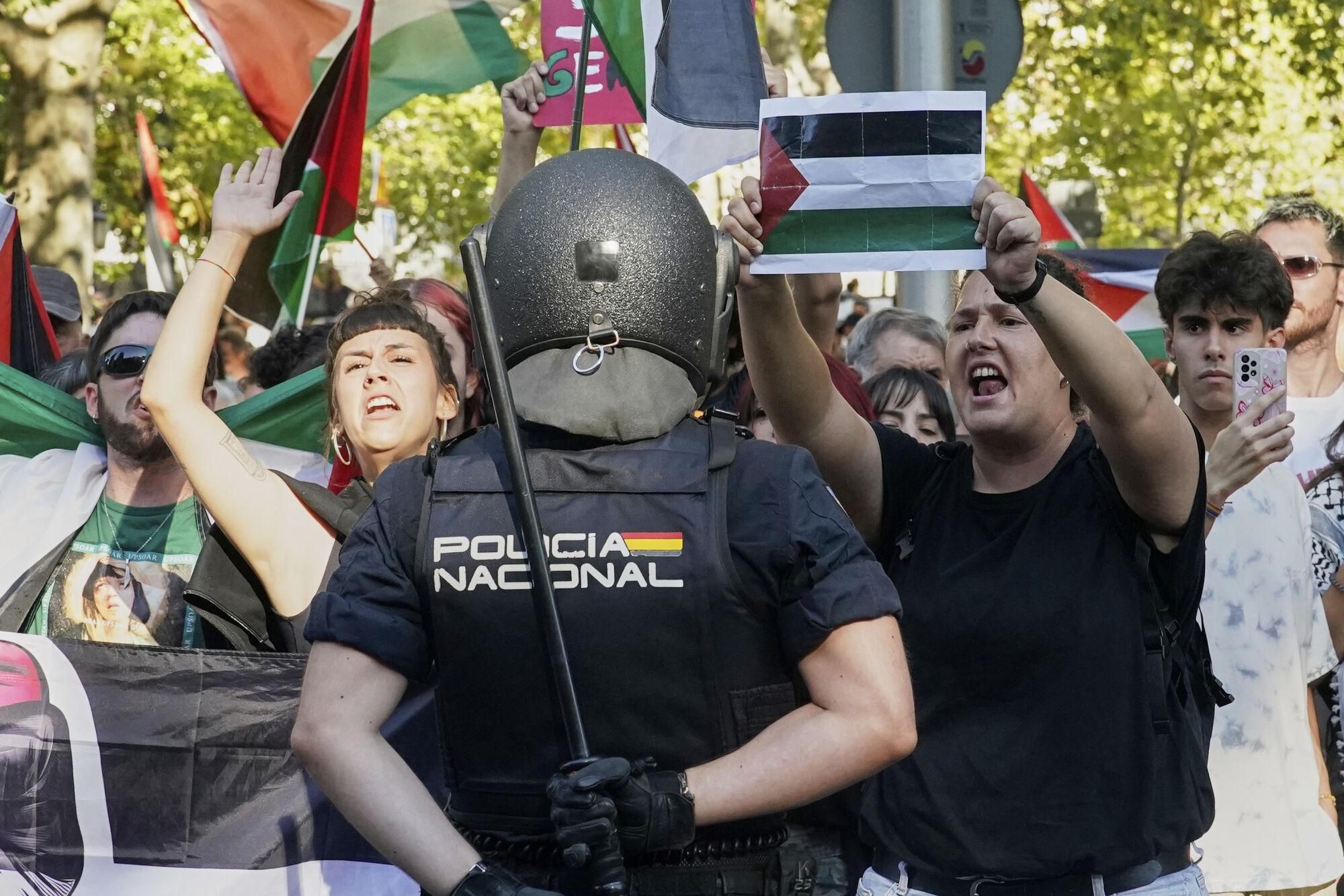 People shout slogans and hold Palestinian flags while protesting during the twenty-first stage of La Vuelta cycling race from Alalpardo to Madrid, Spain, Sunday, Sept. 14, 2025. (AP Photo/Andrea Comas)
