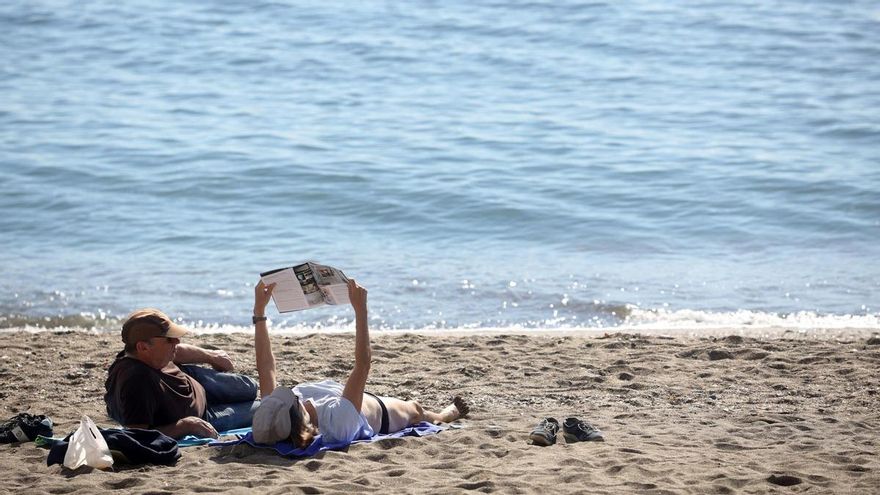 Dos personas disfrutan de las altas temperaturas en la playa de la Malagueta.