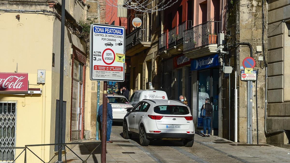 Señal de acceso controlado por cámaras, con vehículos pasando, antes de la hora de cierre.