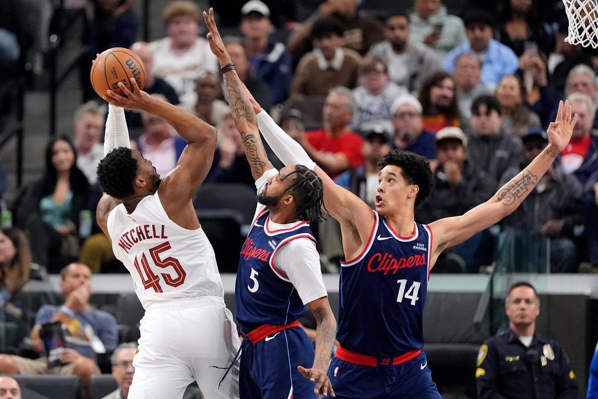 Cleveland Cavaliers guard Donovan Mitchell, left, shoots as Los Angeles Clippers forward Derrick Jones Jr., center, and center Yanic Konan Niederhauser defend during the first half of an NBA basketball game Wednesday, Feb. 4, 2026, in Inglewood, Calif. (AP Photo/Mark J. Terrill)