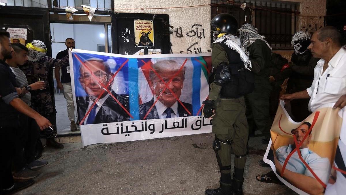 Unos palestinos se disponen a quemar imágenes de Mohamed bin Zayen, Binyamin Netanyahu y Donald Trump, tras conocerse el pacto entre Emiratos Árabes Unidos e Israel.