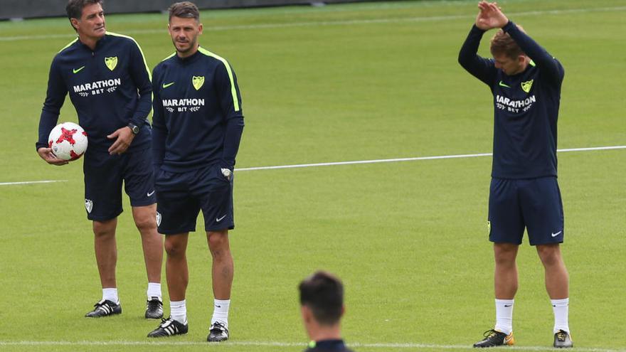 Míchel González, entrenador del Málaga CF, dialoga con Demichelis y Esteban Rolón mientras el centrocampista argentino realiza estiramientos.