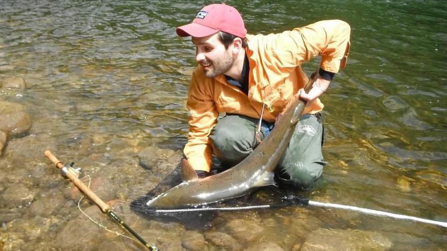 Guy Peters suelta un salmón después de pescarlo con su caña a mosca.