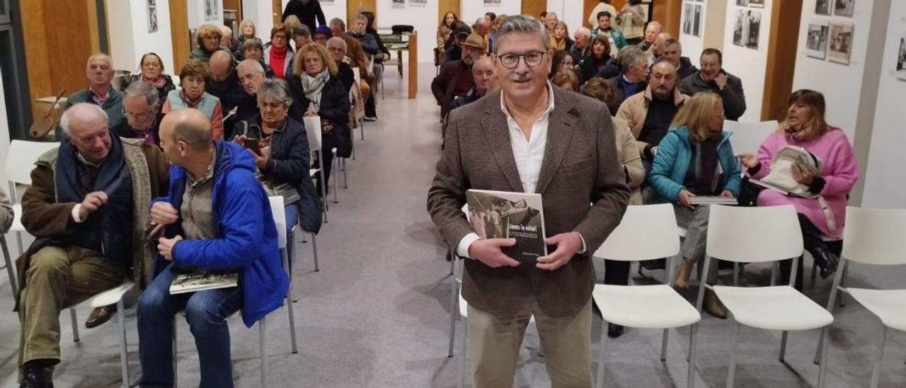 Higinio del Río sostiene su libro, con el público asistente al acto detrás. | Julia Quince