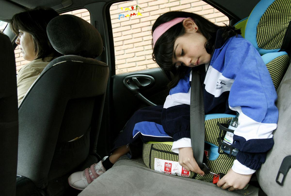 Una niña se pone un cinturón de seguridad en el coche.