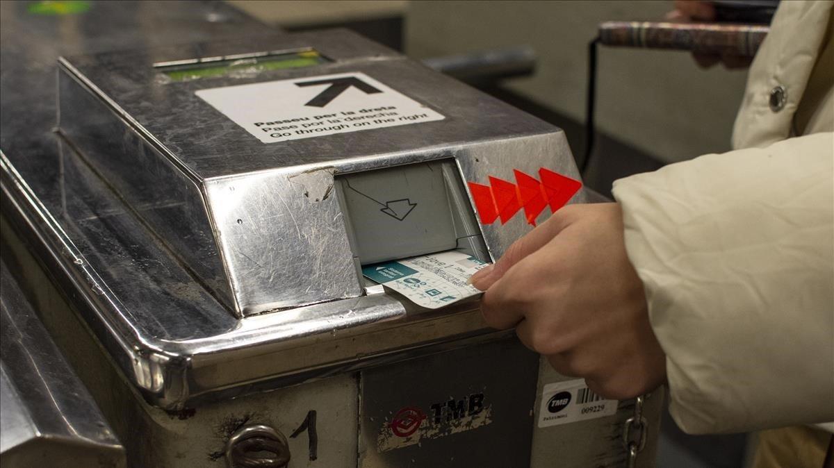 Una usuaria introduce una tarjeta en una máquina de acceso al metro de Barcelona.