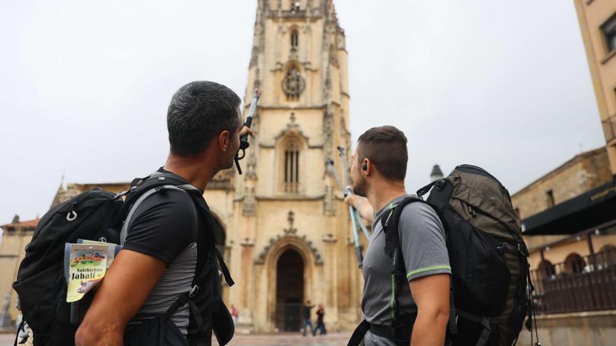 Dos peregrinos, en la plaza de la Catedral, señalando hacia el templo. | MARIO CANTELI