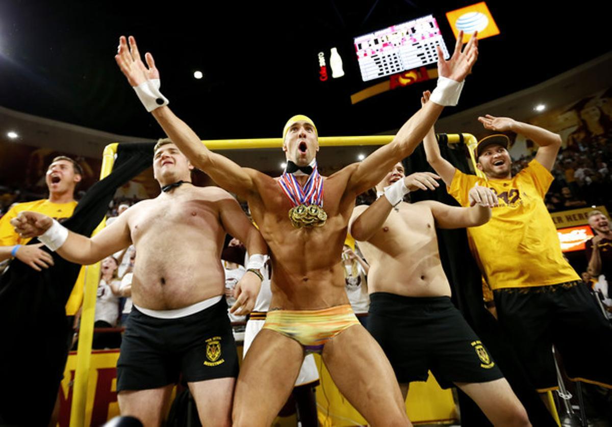 Olympic swimmer Michael Phelps, center, performs behind the Curtain of Distraction during an Oregon State free throw against Arizona State in the second half of an NCAA college basketball game, Thursday, Jan. 28, 2016, in Tempe, Ariz. (AP Photo/Matt York)