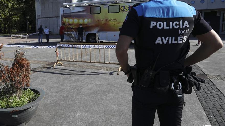 Un agente de la Policía Local de Avilés supervisa el montaje de la unidad móvil montada en La Magdalena para realizar test de covid-19.