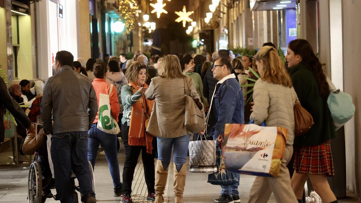 Decenas de personas en la calle Trapería de Murcia, muchas de ellas con bolsas tras comprar, este lunes.