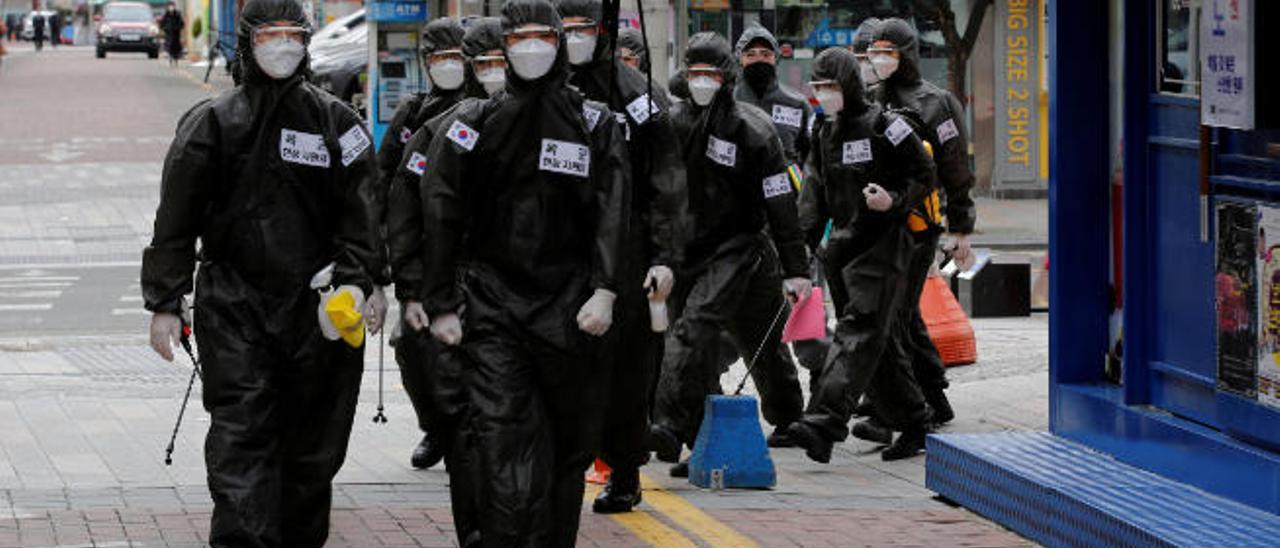 Soldados surcoreanos con sus trajes de protección se disponen a desinfectar las calles de la ciudad de Daegu.