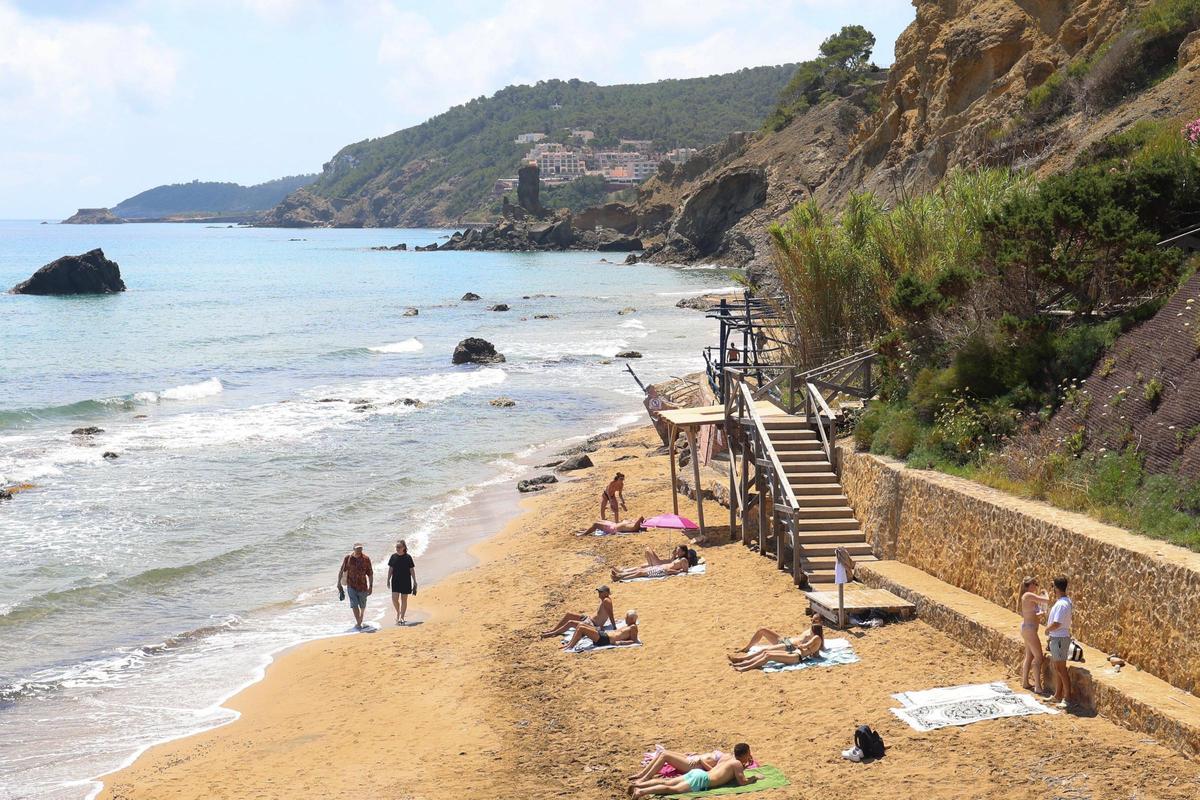 Los turistas toman sol junto al muro de piedra