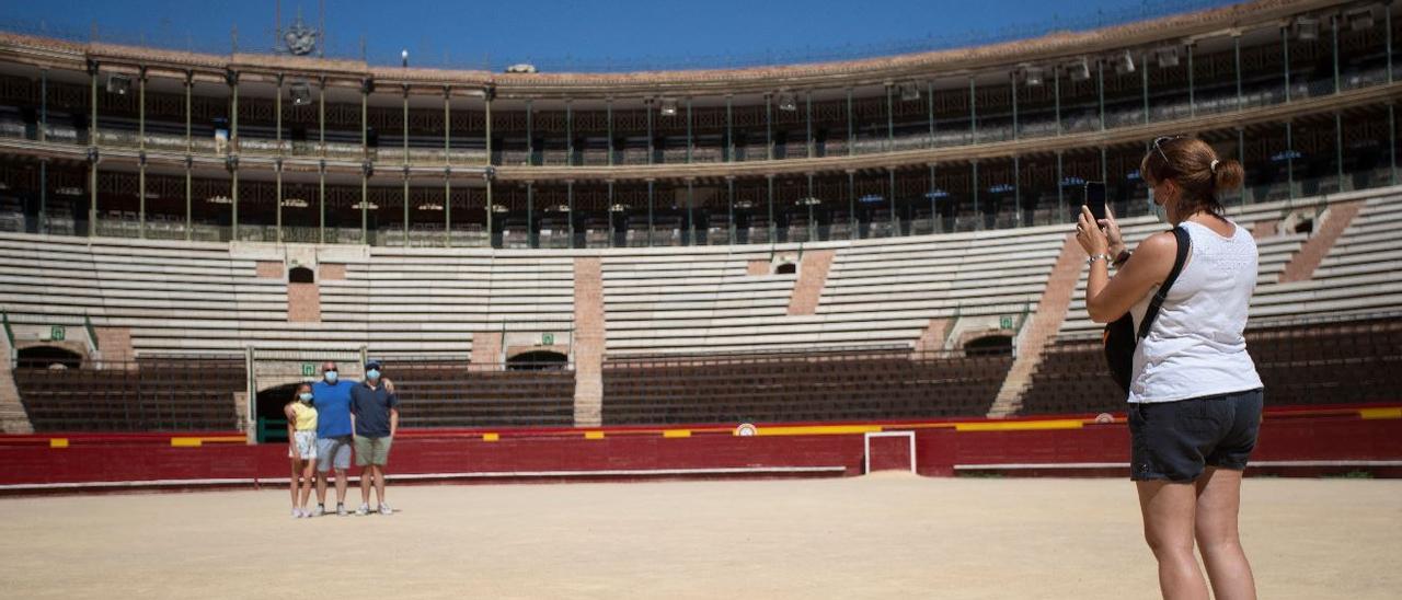 Una familia de turistas se fotografía dentro de la plaza de toros de València durante este verano