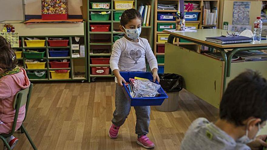 Una niña lleva su material escolar en una caja. | Emilio Fraile