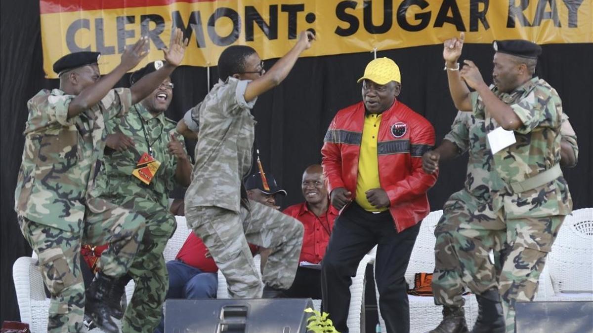 El presidente sudafricano y líder del Congreso Nacional Africano, Cyril Ramaphosa (con chaqueta roja) baila con unos militares durante un mitin de su partido en la ciudad de Durban.