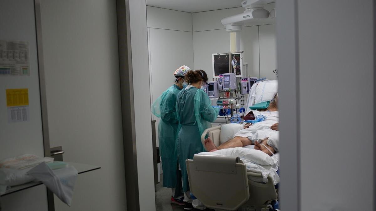 Personal sanitario visita a un enfermo ingresado en la uci del Hospital de la Santa Creu i Sant Pau de Barcelona, el 6 de noviembre del 2020