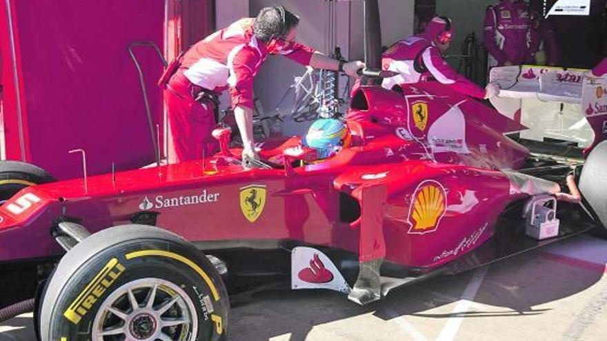 Arriba, dos mecánicos ayudan a Alonso a llevar su coche al garaje. Abajo, Sebastian Vettel. | efe